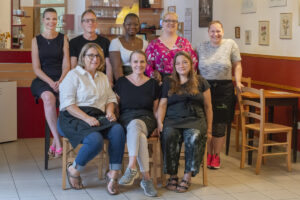 Acht Mitarbeiterinnen und Mitarbeiter des Cafés im Gastraum