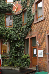 Efeubewachsene Hausfassade mit dem Schild des Café Grenzenlos