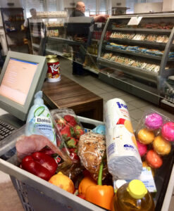 Ein Einkaufskorb mit Obst, Gemüse, Brot und Milch an der Kasse