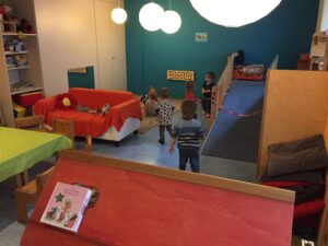 Gruppenraum mit Hochebene, Spieltischen und spielenden Kindern