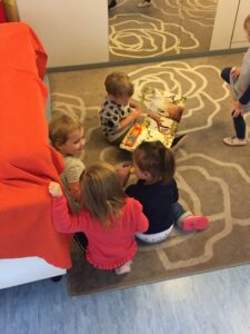 Kinder sitzen mit einem Bilderbuch auf einem Teppich