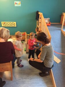 Eine Erzieherin und mehrere Kleinkinder im Gruppenraum