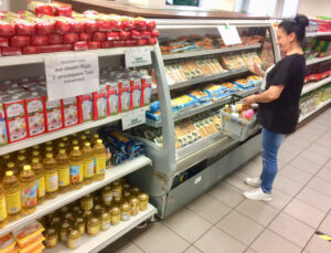 Eine Kundin vor einem Regal mit Getränken und Konserven